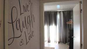 A room with a wall sign saying "Live Laugh Love," a door leading to another room, and a coat hanger in the background.