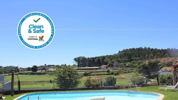 A swimming pool with lounge chairs, surrounded by a grassy area and a hilly landscape in the background.