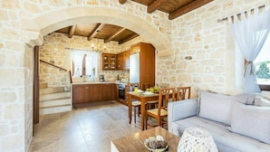 Un intérieur aux murs de pierre comprenant une cuisine, un coin repas et un espace de vie.