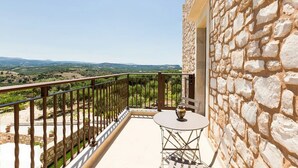 Un balcon avec un mur en pierre, une table et une vue sur la campagne.