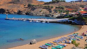 Une plage côtière avec une jetée, des bateaux et des parasols de plage.