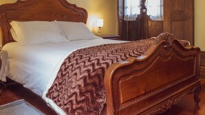A wooden four-poster bed with white linens and a brown patterned throw blanket. - Centennial Holiday House (Porto)
