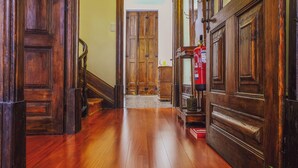 A wooden hallway with a staircase, a fire extinguisher, and a door at the end. - Centennial Holiday House (Porto)