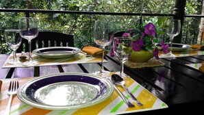 A table set for dining with plates, glasses, and cutlery, surrounded by greenery. - The Mango (Kandy)