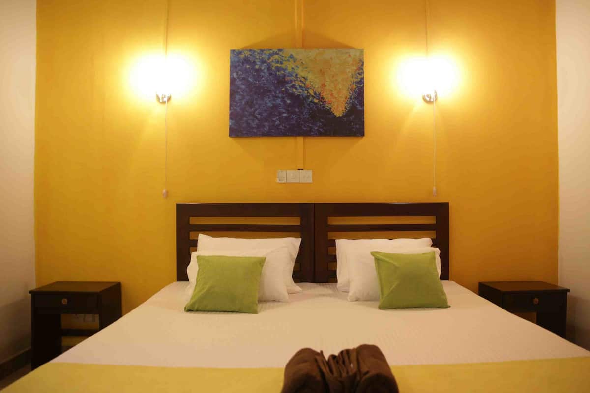 A hotel room with a large bed, two nightstands, a painting on the wall, and two wall-mounted lights.