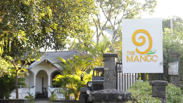 A sign for "The Mango" with a stone gate and lush greenery in the background. - The Mango (Kandy)