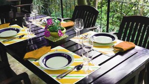 A dining table set with plates, glasses, and cutlery, surrounded by chairs. - The Mango (Kandy)