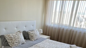 A neatly made bed with a patterned bedspread and pillows, a white headboard, and a nightstand with a lamp.