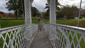 Un pont piétonnier doté de garde-corps en treillis blanc et d’une allée pavée.