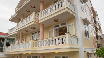 Un immeuble à plusieurs étages doté de balcons, de grandes fenêtres et d’une entrée carrelée.