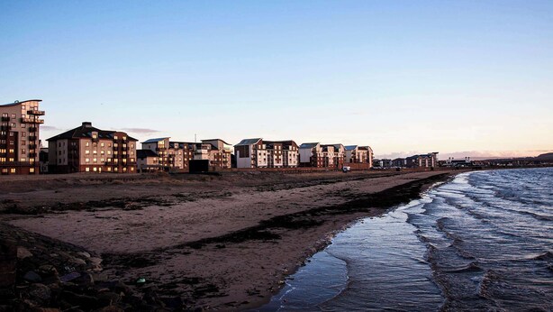 Een hotel aan de kust met meerdere gebouwen, een strand en een rotsachtige kustlijn.
