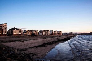Um hotel à beira-mar com vários edifícios, uma praia e um trecho de costa rochosa.