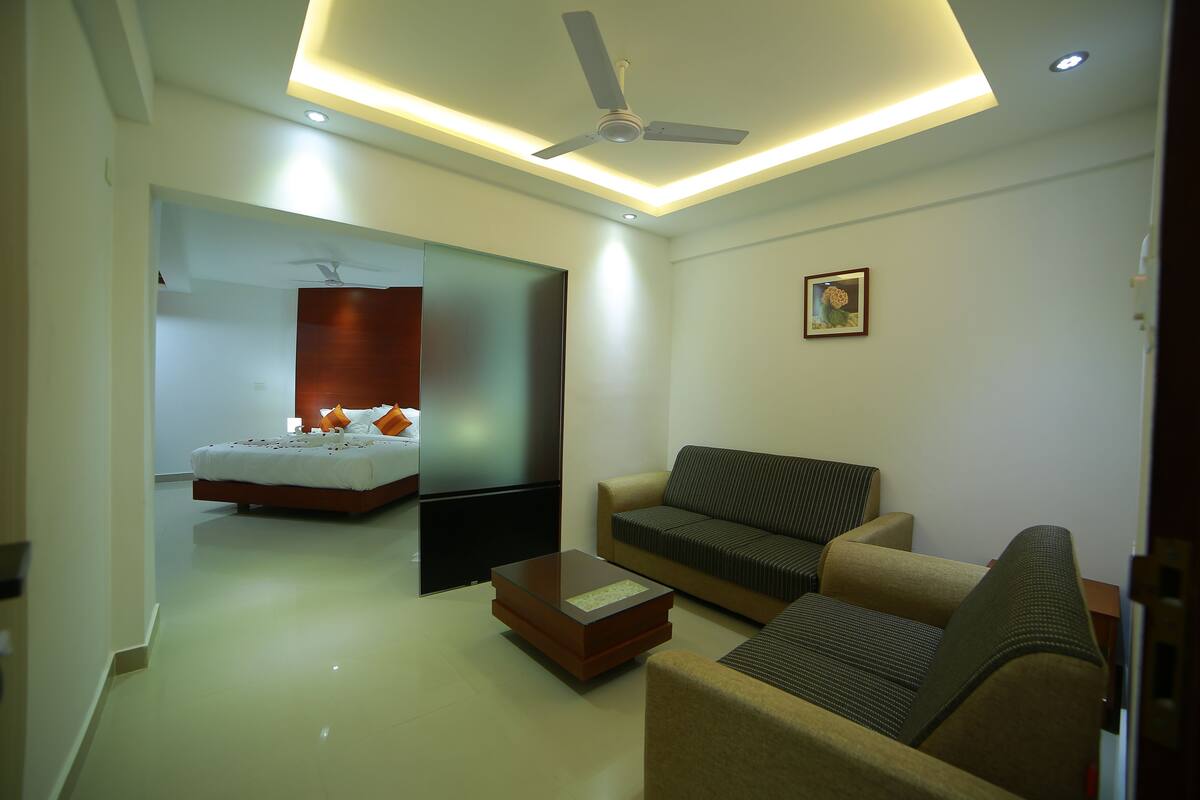 A modern hotel room with a bed, a sofa, a coffee table, and a ceiling fan.