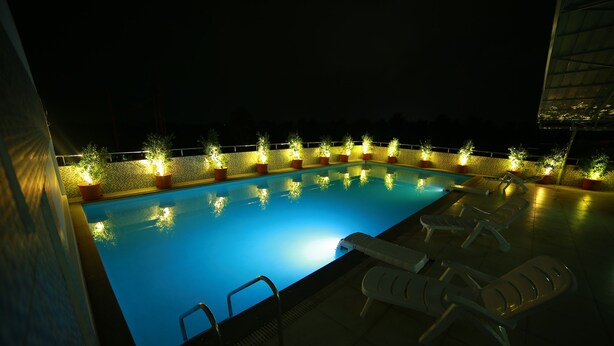 A swimming pool with lights and potted plants around it.
