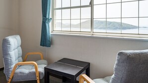 Quarto com vista para um lago e colinas, uma mesa pequena e duas cadeiras.
