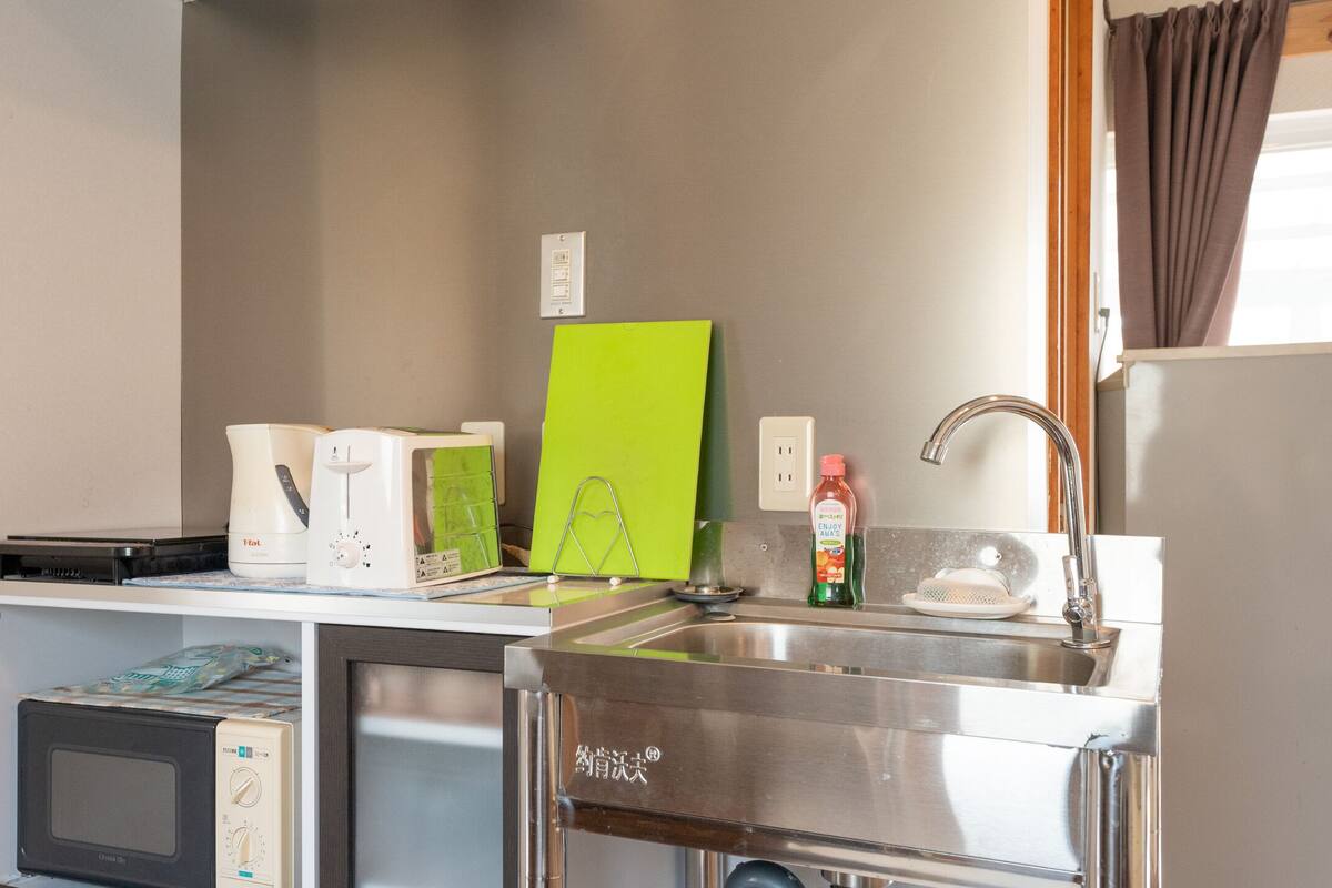 A compact kitchenette with a microwave, toaster, and a small sink.