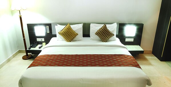 A hotel room with a large bed, two bedside tables, a nightstand, and a lamp. - Hotel Palm Shore (Chittur)
