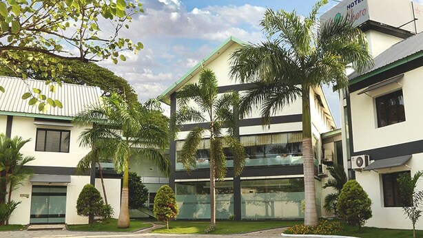 Un hotel de diseño moderno, con un patio central con palmeras y fachada de vidrio.