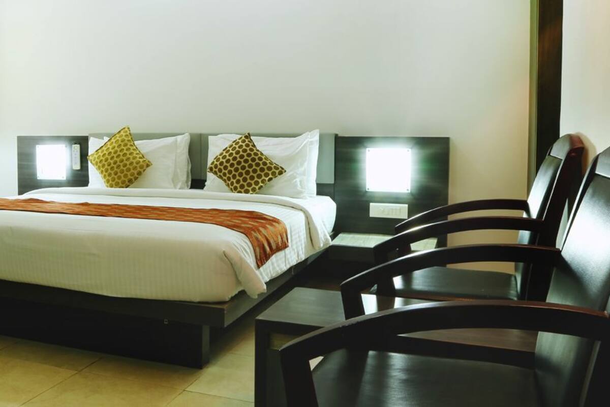 A hotel room with a bed, two bedside tables, a lamp, and two chairs.