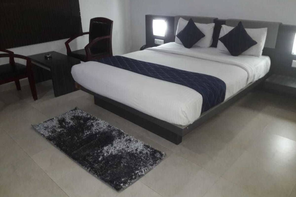 A modern hotel room with a large bed, a small desk, and a chair.