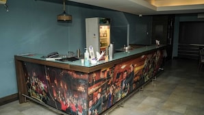Una zona de bar con una barra alargada, un refrigerador y una lámpara colgante.