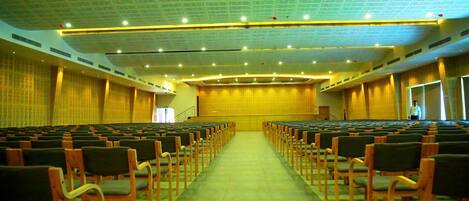 A large hall with rows of chairs and a stage at the front.