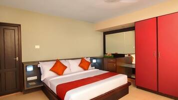 Una habitación de hotel con cama, mesitas de noche, un armario rojo y un espejo.