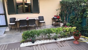 An outdoor patio with a wooden deck, a table with chairs, and potted plants. - Holiday house in residence near the sea (Borgo Hermada 29)