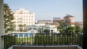 Ein Balkon mit Metallgeländer, der auf einen Wohnbereich mit Gebäuden und einem Schwimmbecken blickt.