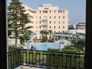 Un hotel con piscina, un edificio con varios balcones y un jardín bien cuidado.