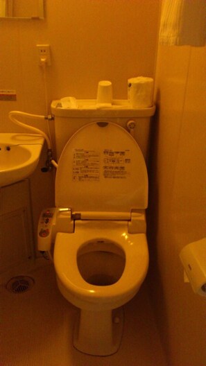 A standard bathroom with a toilet, sink, and a paper towel dispenser. - Business Hotel Chateau Est Takamatsu (Takamatsu)