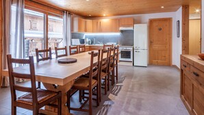 A wooden-paneled kitchen with a dining table and chairs, a refrigerator, and a microwave. - Top location in the resort center with easy access to slopes (Morzine)