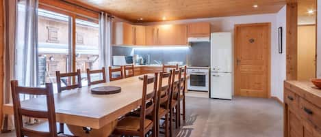 Una cocina amplia con armarios de madera, una mesa de comedor con sillas y un refrigerador.