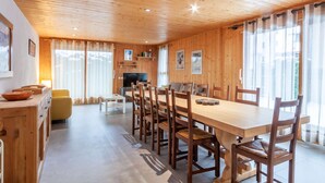 A wooden-paneled room with a dining table, chairs, a sofa, and a TV. - Top location in the resort center with easy access to slopes (Morzine)