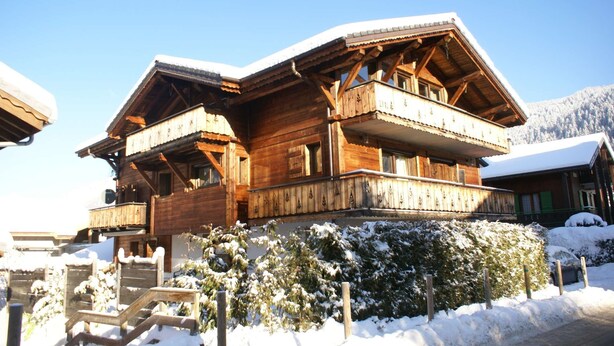 A wooden chalet with a balcony, surrounded by snow-covered trees and a clear sky. - Top location in the resort center with easy access to slopes (Morzine)