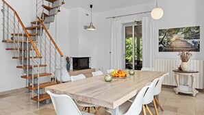 Een moderne keuken met een houten tafel, witte stoelen en een trap met houten treden.