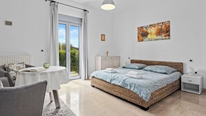 Een slaapkamer met een groot bed, een nachtkastje, een stoel, een klein tafeltje en uitzicht op het landschap.