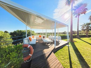 An outdoor patio with a covered seating area, white furniture, and a lifebuoy.