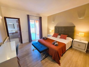 Ein Hotelzimmer mit Bett, Nachttischen, Schreibtisch und einer Bank.