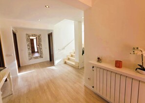 Ein modernes Interieur mit Treppe, einem Flur, der in einen Raum führt, und einem Heizkörper an der Wand.