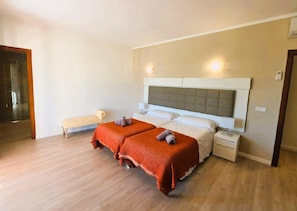 Une chambre d’hôtel avec un grand lit, des tables de chevet, un banc et un espace douche.