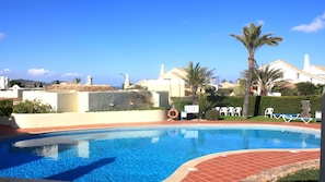 A swimming pool with a tiled edge, surrounded by palm trees and lounge chairs. - La Manga Club - El Rancho Detached Villa free wifi, sky sports, lovely views.  (Murcia)