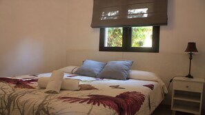 A bedroom with a bed, pillows, a bedside table with a lamp, and a window with a view of greenery. - La Manga Club - El Rancho Detached Villa free wifi, sky sports, lovely views.  (Murcia)