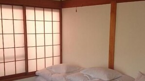 A traditional Japanese room with tatami flooring, a futon bed, shoji screens, and a ceiling fan. - Moto-Hakone Guest House (Hakone)