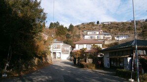 A street with houses, a crosswalk, and a small building with a sign. - Moto-Hakone Guest House (Hakone)