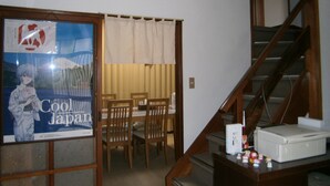 A room with a dining area, a staircase, and a poster on the wall. - Moto-Hakone Guest House (Hakone)