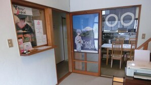 A room with a sliding door leading to a kitchen area. There is a poster on the door advertising 'Cool Japan'. - Moto-Hakone Guest House (Hakone)