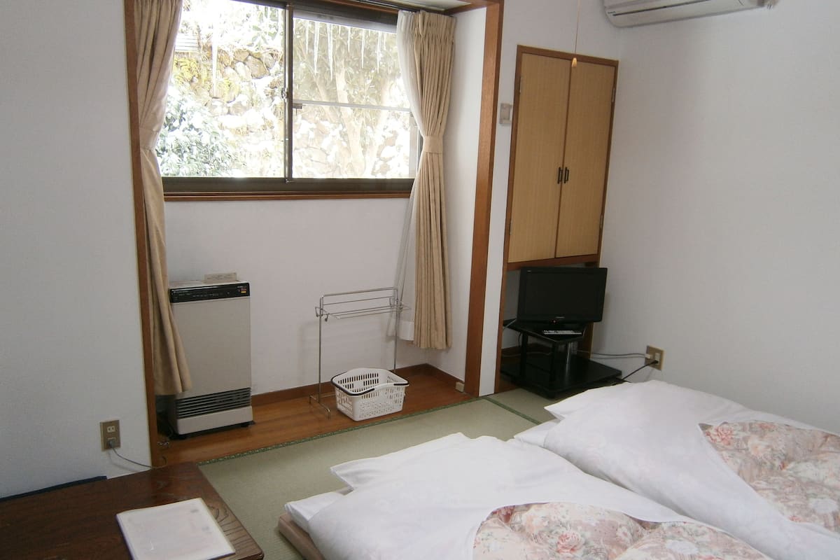 A hotel room with a bed, a desk, a TV, a wardrobe, and a window with curtains.