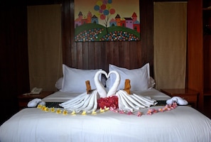 Habitación de hotel con una cama decorada con una grúa de toallas y un ramo de flores.