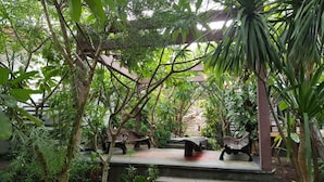 A garden with stone benches and a pergola. - Exotic Komodo Hotel (Labuan Bajo)